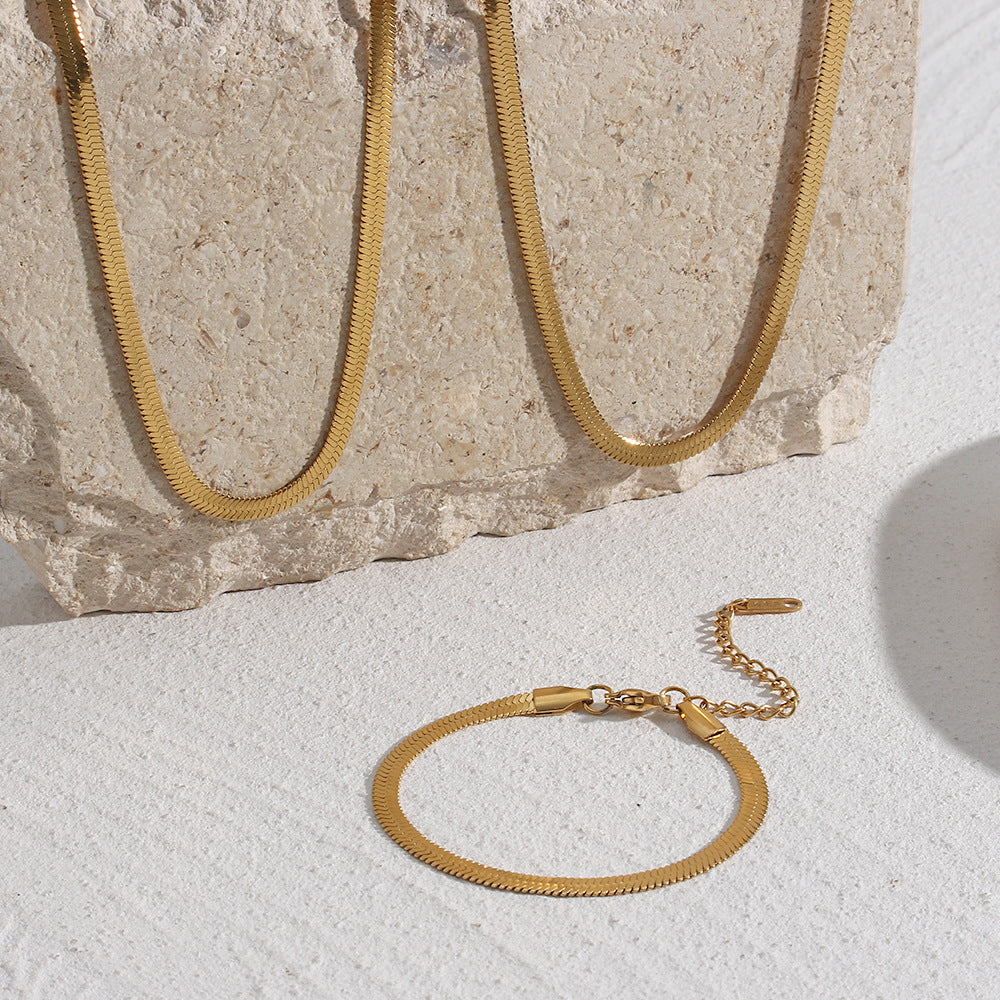 Set of gold plated snake chain on beige and white background from Aurie Jewelry Essential Collection